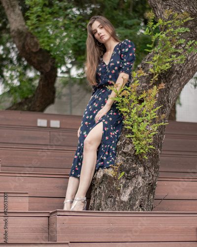 Mulher jovem posando encostada em um árvore com fundo desfocado. photo