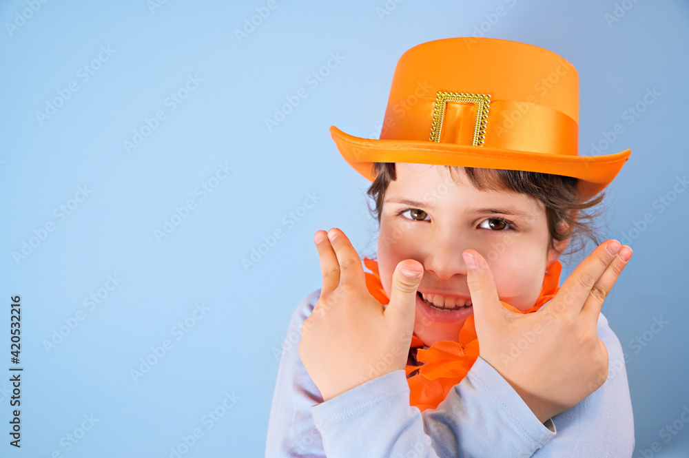 King's Day in Holland, traditional festival on April 27 in the Netherlands. Little girl in a festive orange hat on a blue background eats colored donuts. Copy space King's Day in Holland, traditional festival on April 27 in the Netherlands. Little girl in a festive orange hat on a blue background eats colored donuts. Copy space