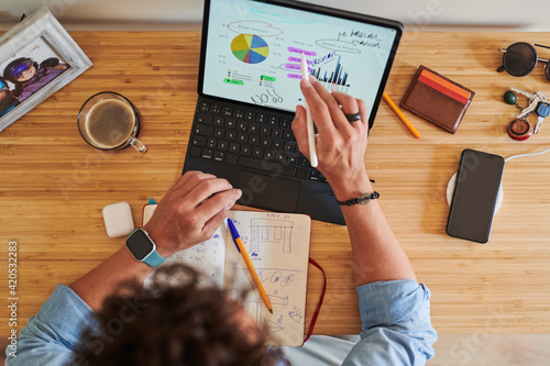 Unrecognizable worker making notes on graphs on tablet photo