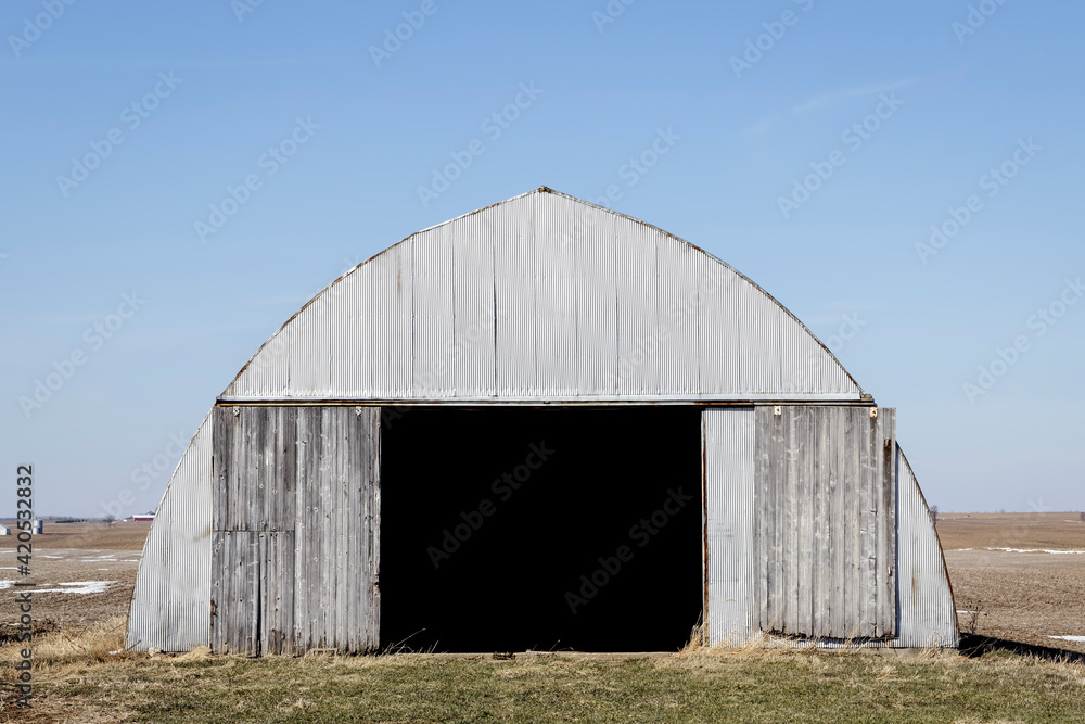 Corrugated Metal Farm Building in a Field under a Blue Sky