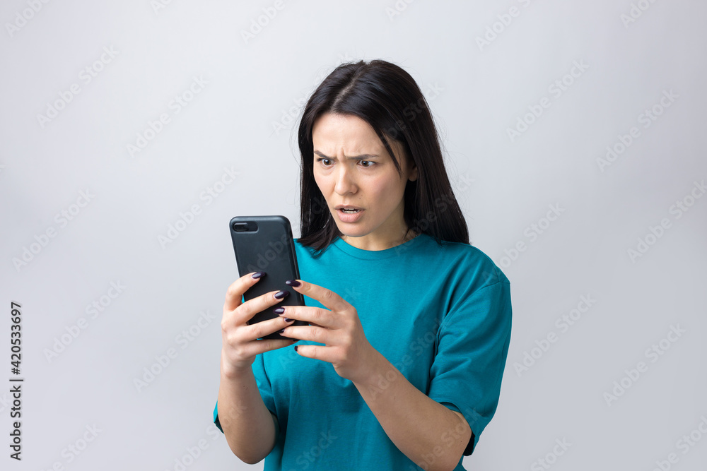 Front portrait of young smiling woman using mobile phone against grey background Front portrait of young smiling woman using mobile phone against grey background