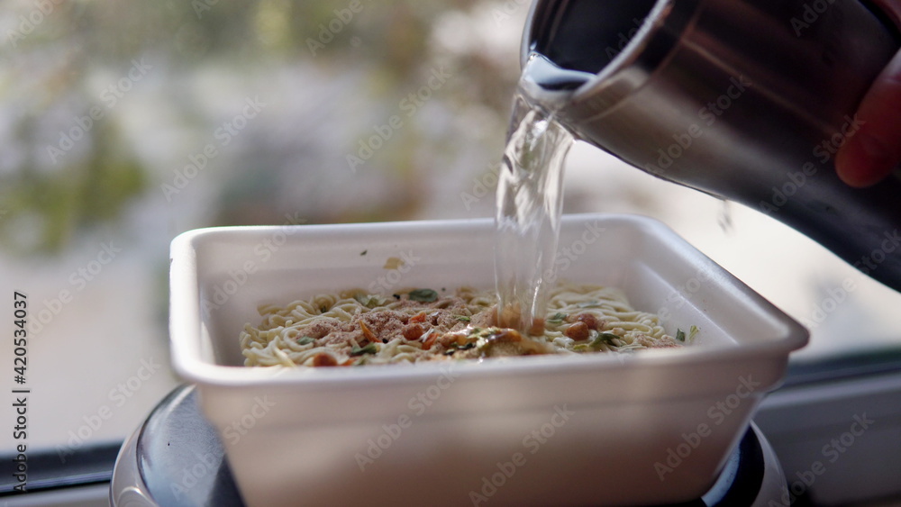 Adding boiling water to the top ramen. Brewing instant noodles Stock