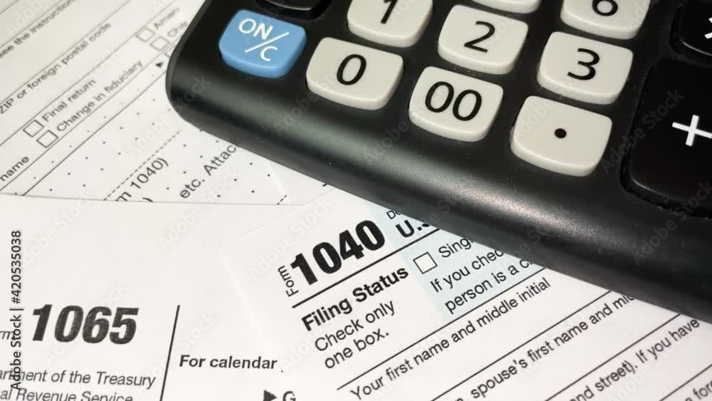 Man counting taxes on a calculator, documents on the table, tax form 1040 close up Man counting taxes on a calculator, documents on the table, tax form 1040 close up