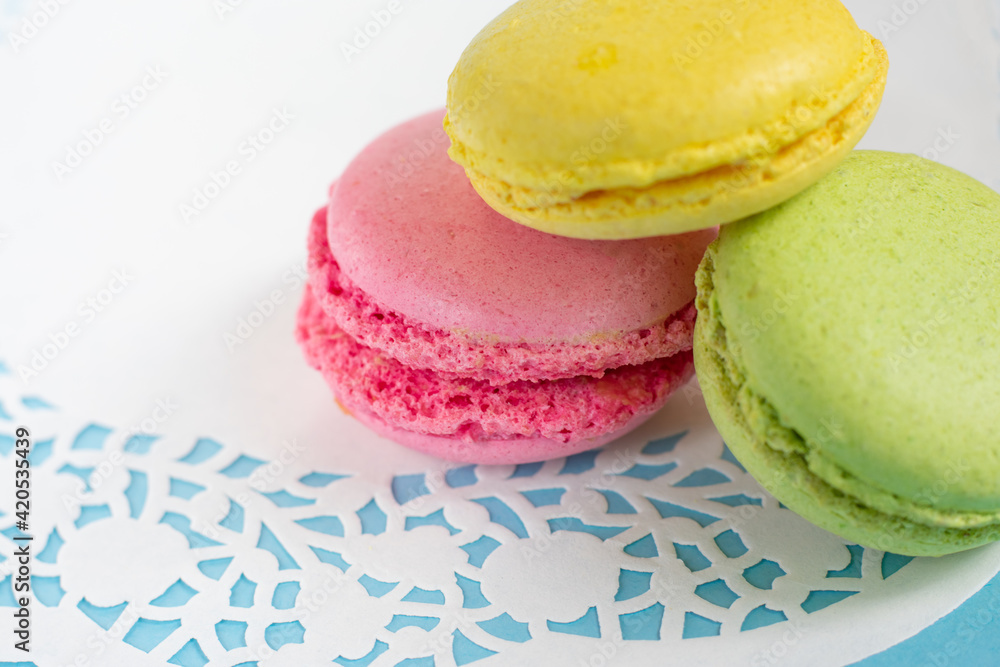 Colorful almond macarons on white napkin on blue background. French meringue cookies Colorful almond macarons on white napkin on blue background. French meringue cookies