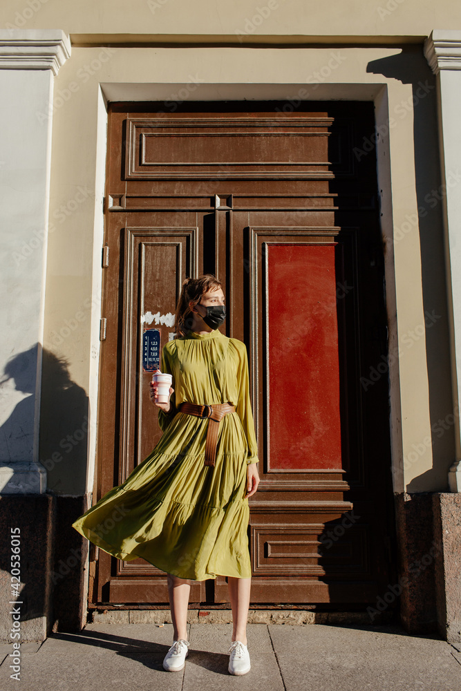 Young woman with cup of coffee standing near old building Young woman with cup of coffee standing near old building