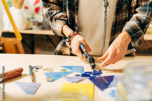 Woman putting out a mosaic of glass with tweezers, fusing, craftsmanship