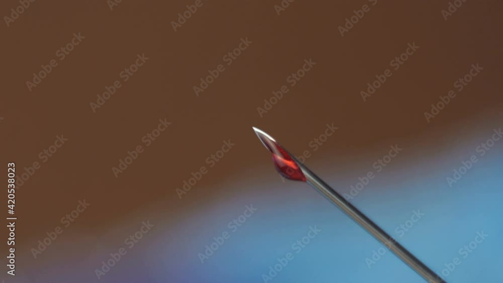 Close-up of a drop of vaccine sticking from the tip of a needle from a syringe. Close-up of a needle from a syringe with which a vaccine is dripping. Close-up of a drop of vaccine sticking from the tip of a needle from a syringe. Close-up of a needle from a syringe with which a vaccine is dripping.