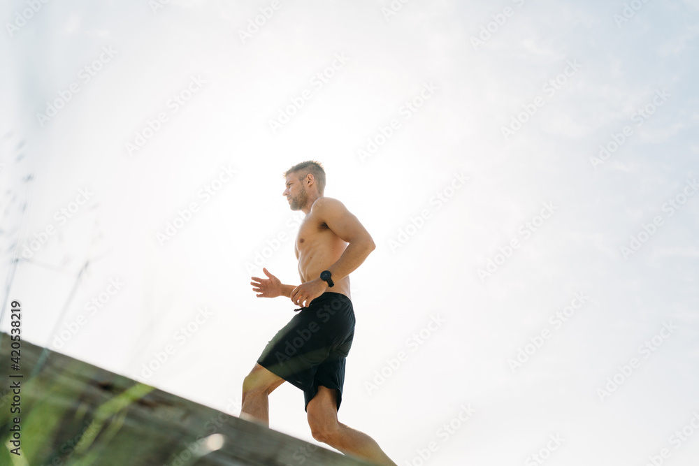 Male athlete running uphill on sunny day