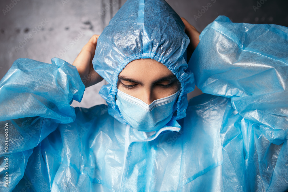 Fototapeta premium Nurse doctor wear protective medical suit. Male medic dressed blue face surgical mask. Coronavirus concept. Man ready to heal patients due to covid. Pandemic disease flu