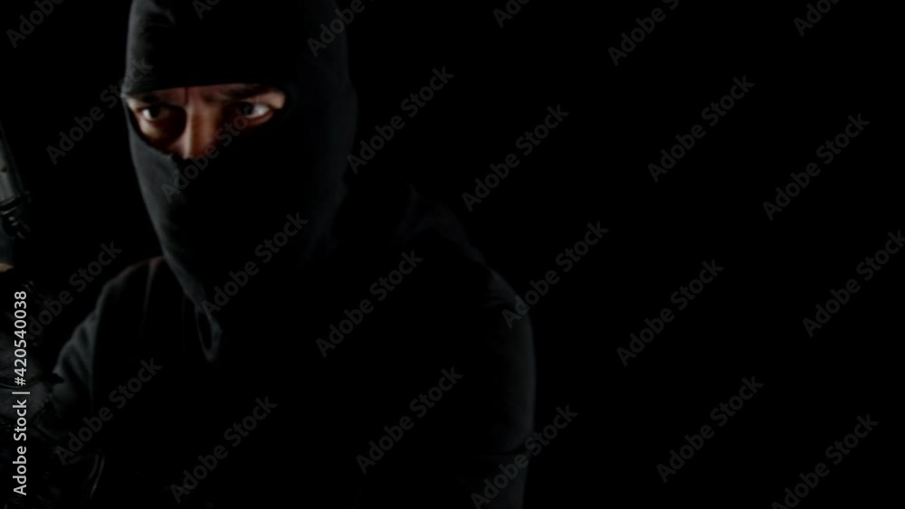 Thief with balaclava and gun in the dark with threatening look. Thief with balaclava and gun in the dark with threatening look.