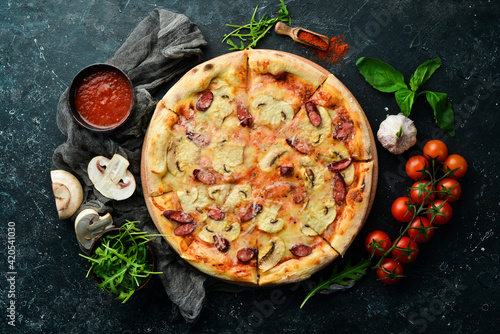 Homemade Pizza with sausages, mushrooms and cheese. On a black stone background. Free space for text.