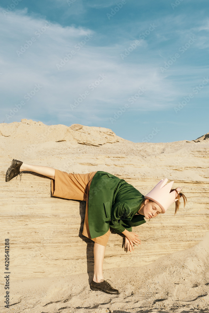 Creative Fashion portrait of Woman in crown near sandy hill