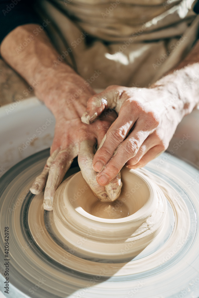 Potter’s hand correcting during shaping clay blank on a potter's wheel