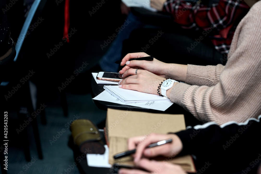 A group of young people records a lecture at a business training. Their hands are depicted with notebooks and pens....... A group of young people records a lecture at a business training. Their hands are depicted with notebooks and pens.......