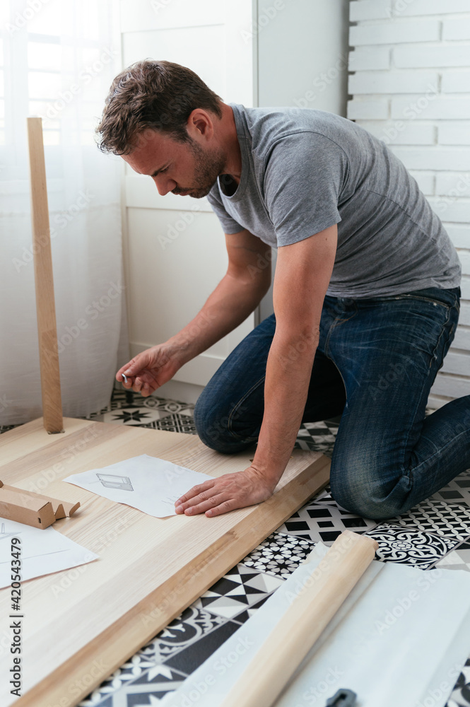 Focused man installing table at home Focused man installing table at home