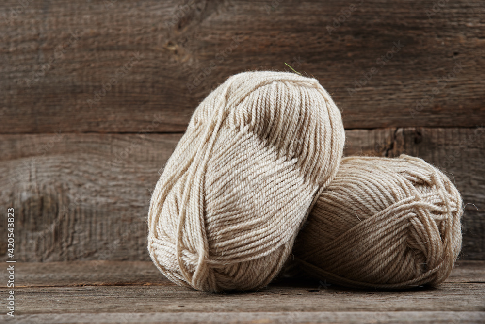 Two skeins of woolen yarn and needles for knitting on a wooden background Two skeins of woolen yarn and needles for knitting on a wooden background