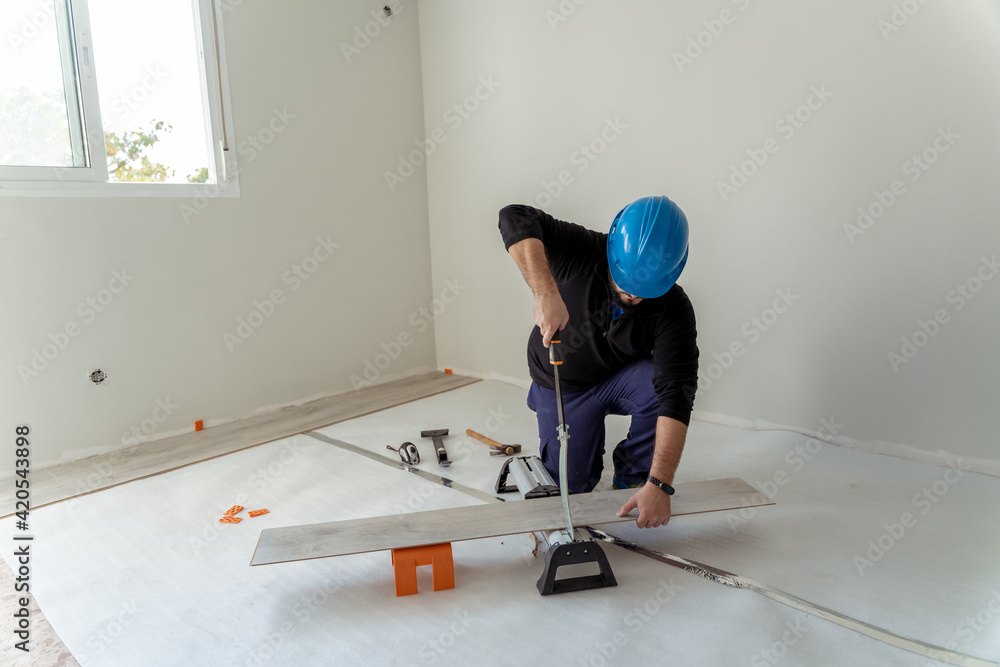 carpenter cutting a sheet of wood to install the flooring in a home renovation