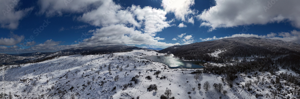 Drone shooting at 180 degrees of the Biviere lake in the heart of the Nebrodi mountains in winter. View of Etna and the Aeolian Islands. Sicily in winter. Sicilian mountains.