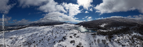 Drone shooting at 180 degrees of the Biviere lake in the heart of the Nebrodi mountains in winter. View of Etna and the Aeolian Islands. Sicily in winter. Sicilian mountains.