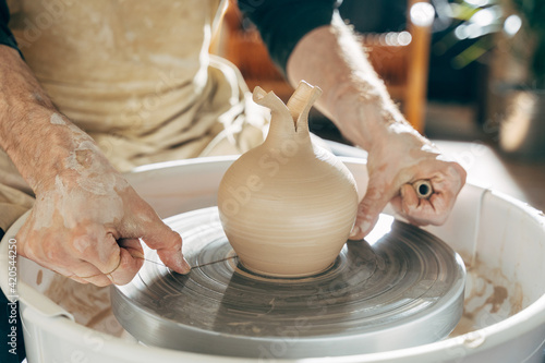 Cropped view of the man sitting at his workshop and making vase