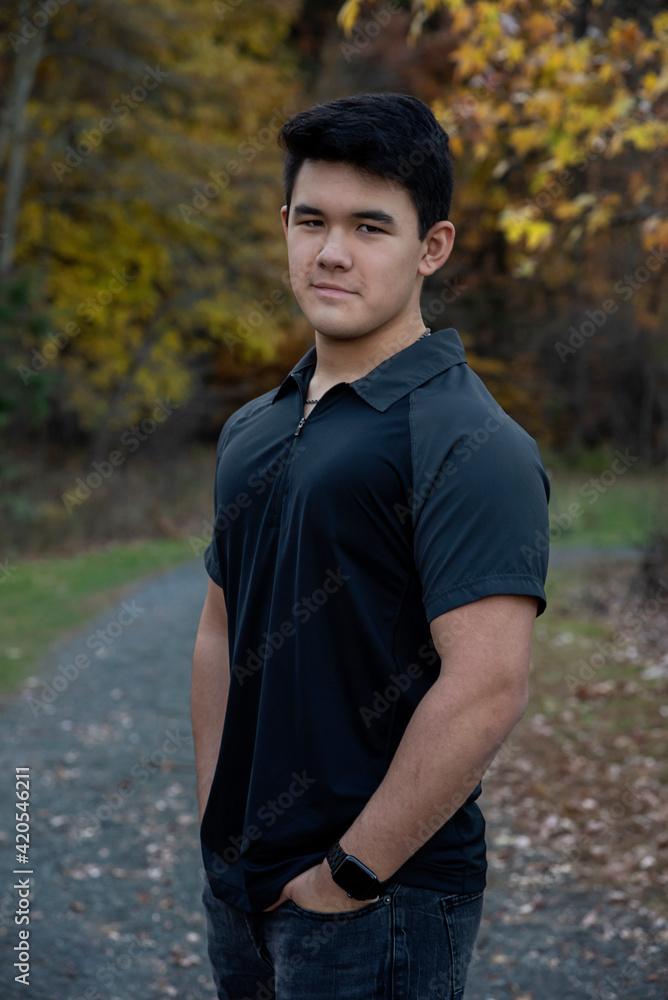 Outdoor lifestyle portrait of handsome young man wearing short sleeve black shirt looking at camera with path in background