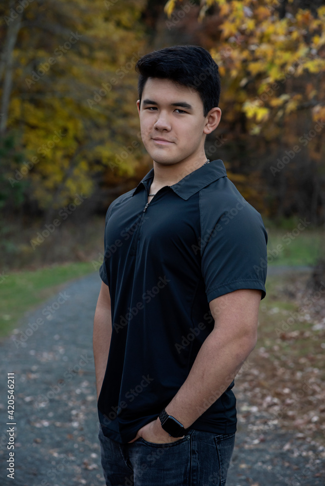 Outdoor lifestyle portrait of handsome young man wearing short sleeve black shirt looking at camera with path in background Outdoor lifestyle portrait of handsome young man wearing short sleeve black shirt looking at camera with path in background