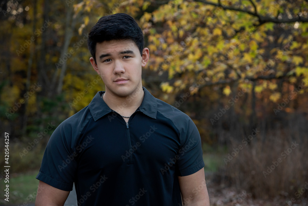 Outdoor lifestyle portrait of handsome young man wearing short sleeve black shirt looking at camera