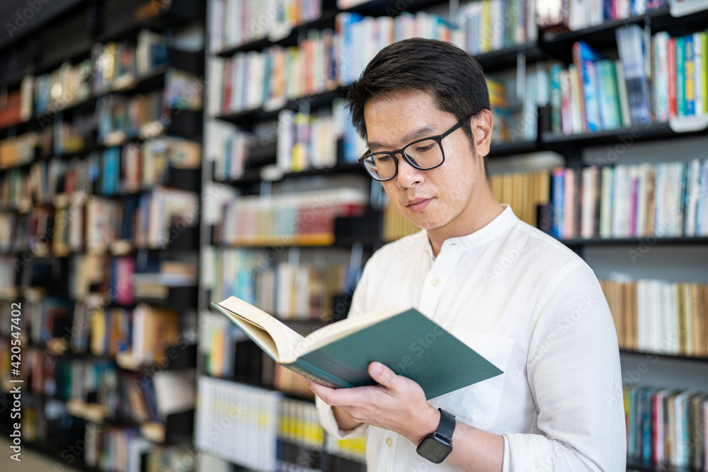A man is reading a book in the university library. A man is reading a book in the university library.