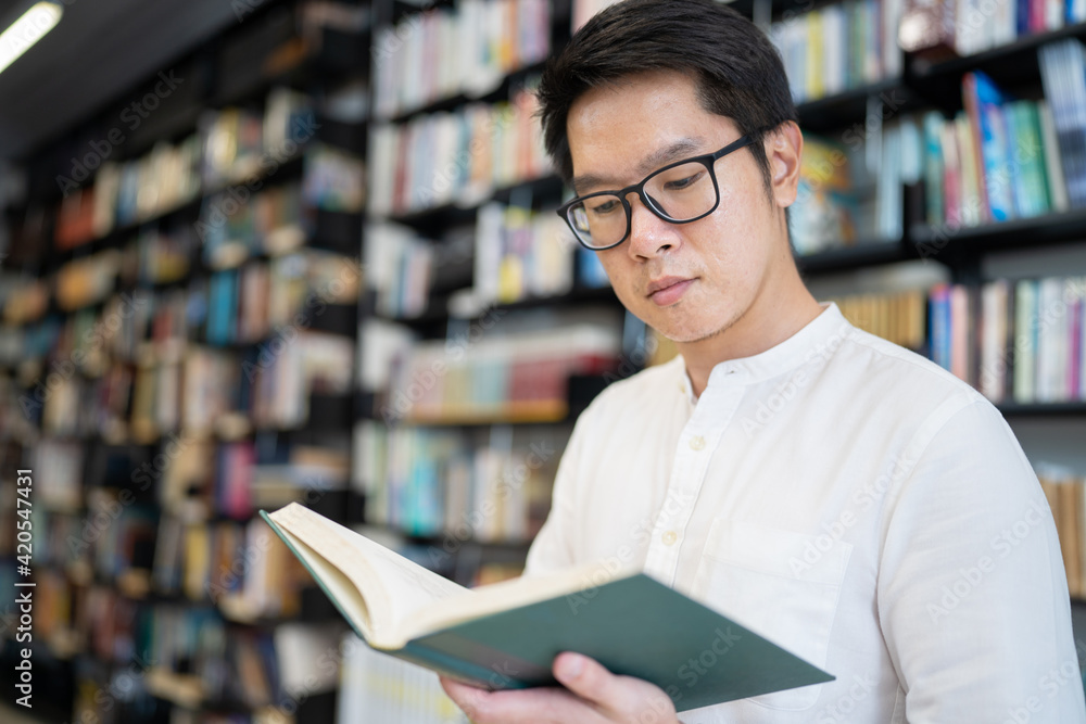 A man is reading a book in the university library. A man is reading a book in the university library.