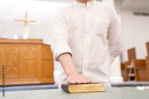 A man is reading the Holy Bible and praying in a worship room in a Christian church.