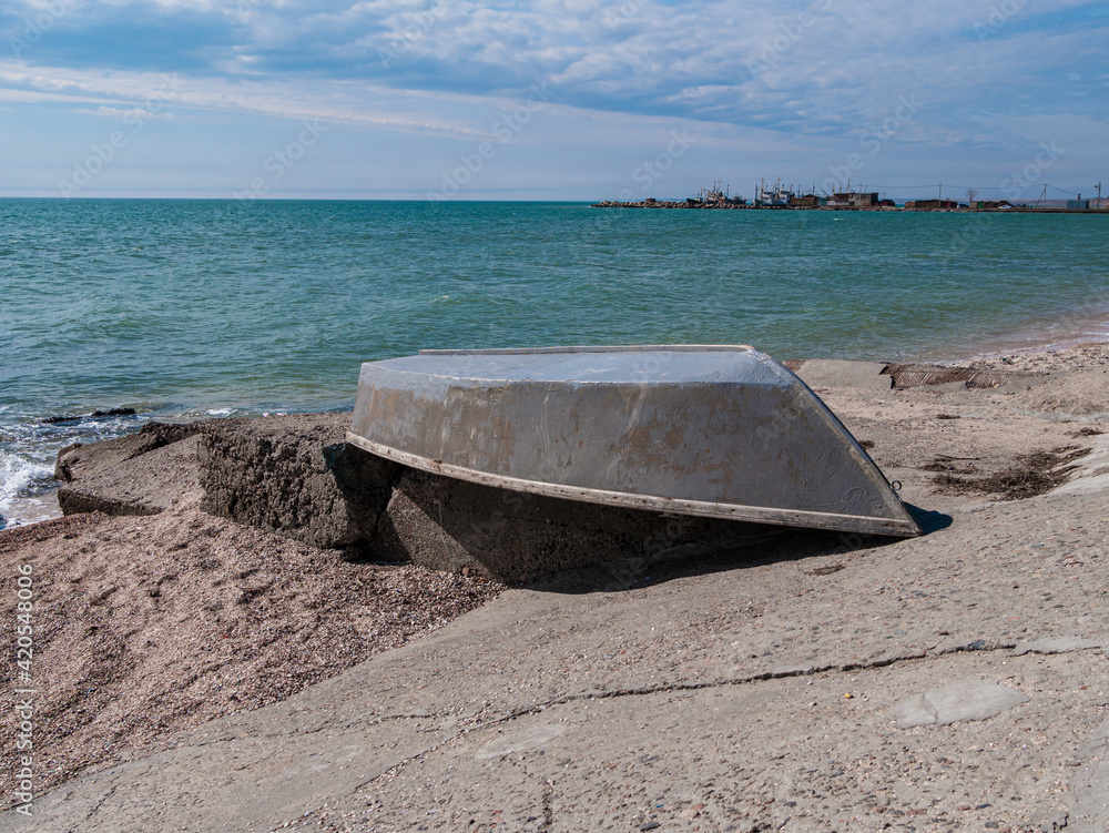 Gray boat on an empty sand beach. Cloudy sky vivid blue water. Fishing concept. Marine wallpaper copy space. Ship on a beach on a sunny day. Travel lifestyle photo. Gray boat on an empty sand beach. Cloudy sky vivid blue water. Fishing concept. Marine wallpaper copy space. Ship on a beach on a sunny day. Travel lifestyle photo.