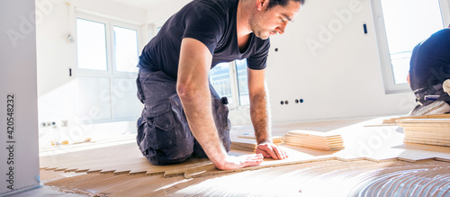 Handwerker verlegt parkettboden in einem Haus.