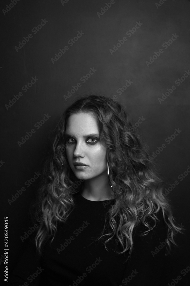 Vintage style black and white portrait of beautiful young girl with long curly hair and smoky eye makeup