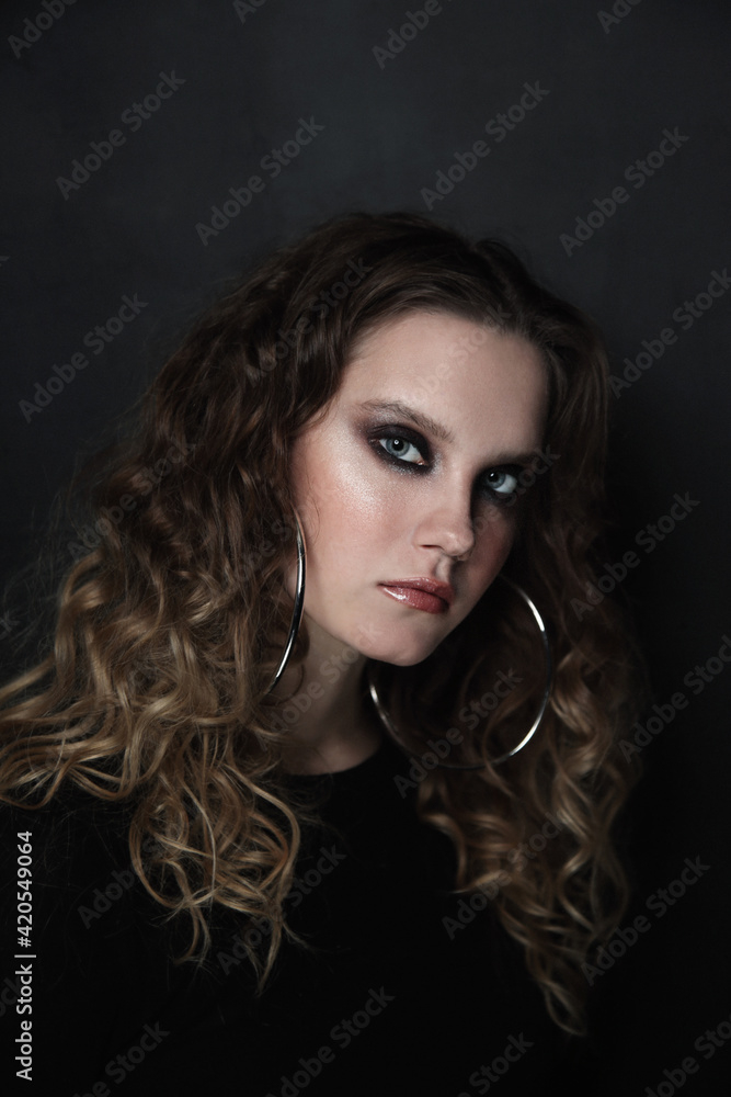 Vintage style portrait of beautiful young girl with smoky eye makeup and fancy ring earrings, selective focus, grainy