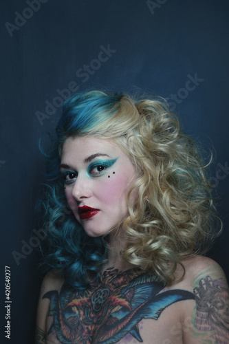 Portrait of beautiful tattooed young woman with fancy makeup and hairdo