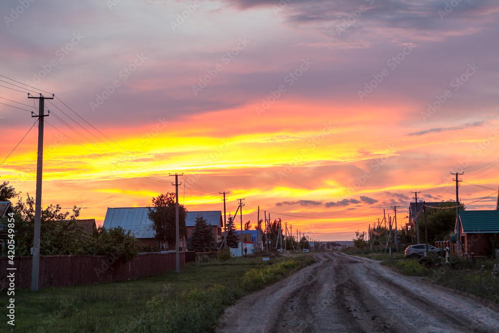 Village with gravel road and setting sun, Russian settlement