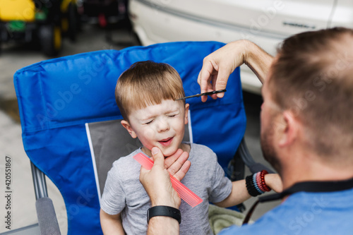 father giving his son a haircut in the garage