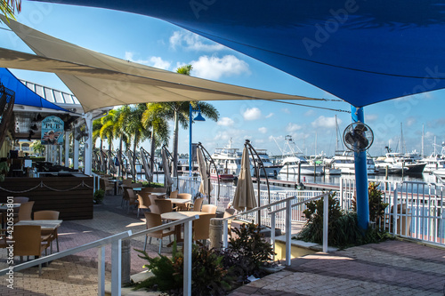 Downtown historic Stuart, Florida. Restaurants on the St. Lucie River with outdoor eating areas covered with blue awnings, yachts in the marina, lifestyle at the waterfront town in eastern Florida