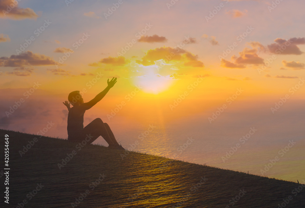 Happy man with arms outstretched to the sunset. salvation, and happiness concept 