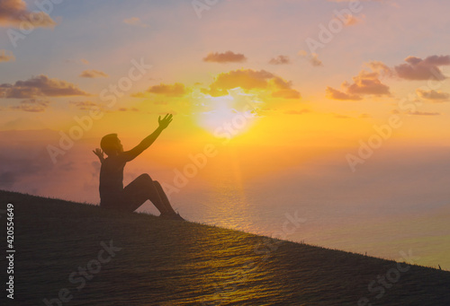 Happy man with arms outstretched to the sunset. salvation, and happiness concept 