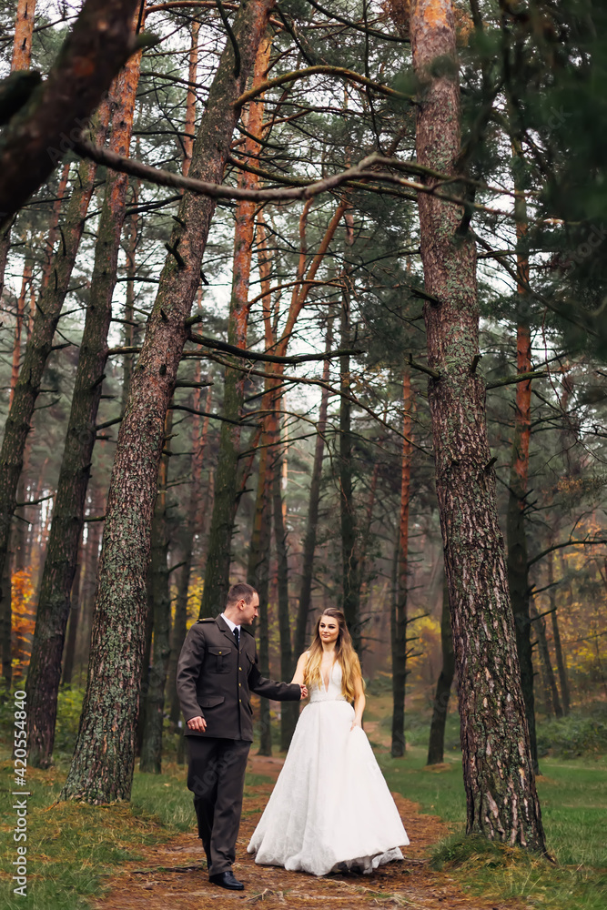the groom in uniform holds bride hand in a wedding dress. newlyw the groom in uniform holds bride hand in a wedding dress. newlyw