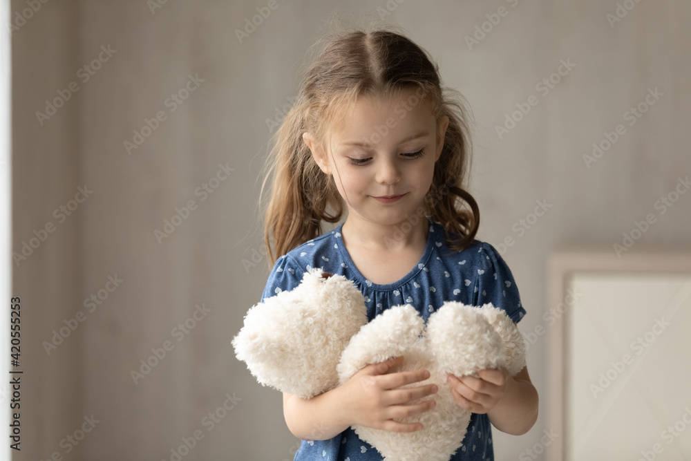 Cute little 7s girl kid hold fluffy animal toy have fun engaged in playful activity at home on weekend. Small Caucasian preschooler child play with stuffer teddy bear. Entertainment concept. Cute little 7s girl kid hold fluffy animal toy have fun engaged in playful activity at home on weekend. Small Caucasian preschooler child play with stuffer teddy bear. Entertainment concept.