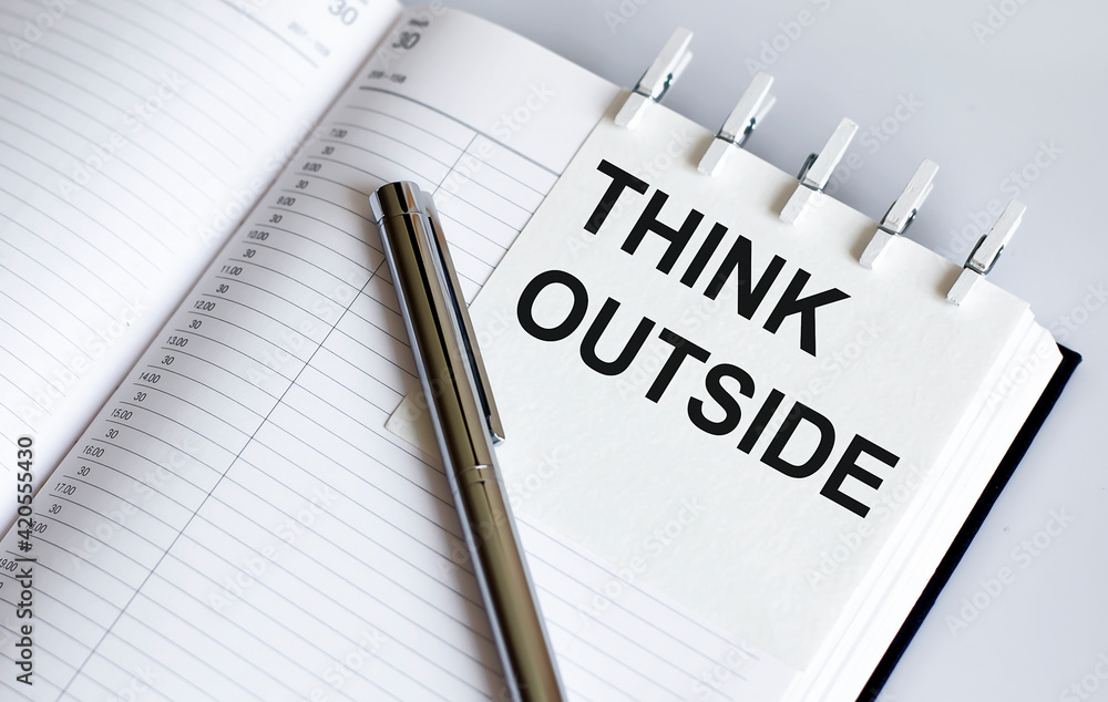 text Think Outside on the short note texture background with pen text Think Outside on the short note texture background with pen
