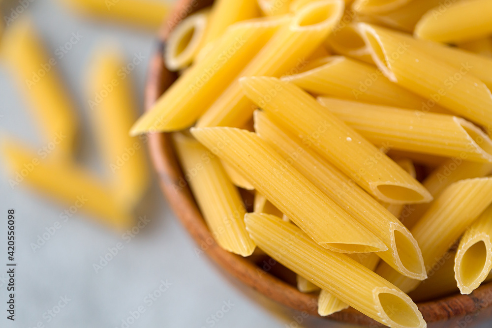 Flat lay of bowl with raw penne pasta on ultimate gray Flat lay of bowl with raw penne pasta on ultimate gray