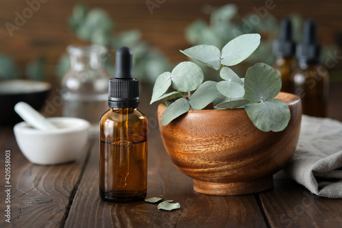 Fotografie Dropper bottle of eucalyptus essential oil and wooden bowl of green eucalyptus leaves