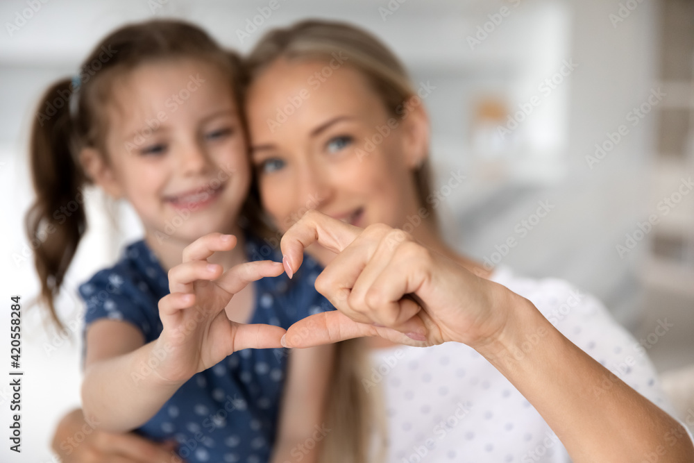Close up of smiling young Caucasian mom and little daughter make heart love hand gesture demonstrate care and affection. Happy mother and small girl child hug embrace. Gratitude concept. Close up of smiling young Caucasian mom and little daughter make heart love hand gesture demonstrate care and affection. Happy mother and small girl child hug embrace. Gratitude concept.