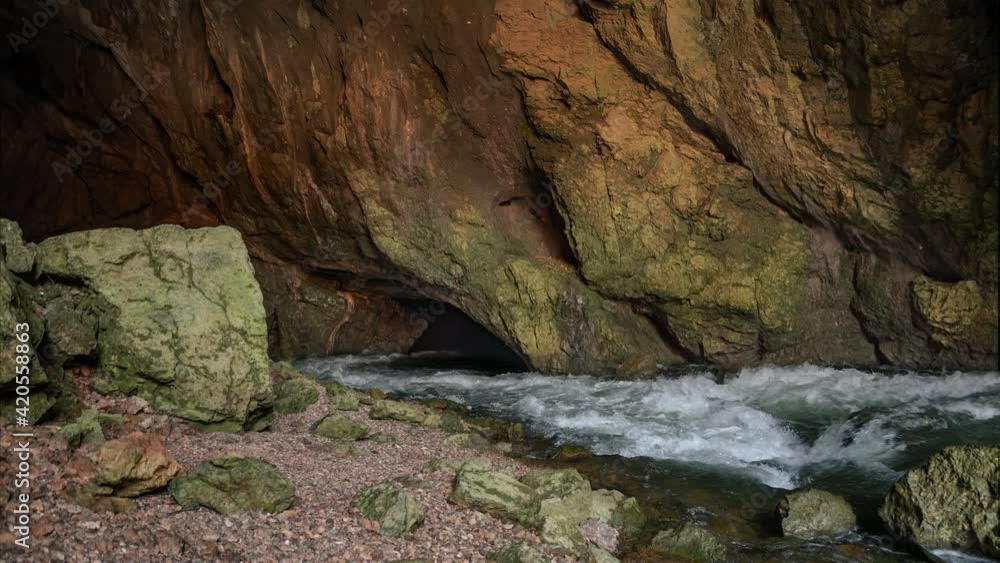Wild river Rak flowing in Weaver Cave entrance, Rakov Skocjan. Karst spring with clean and fresh water in Slovenia. Beautiful nature deep in underground. Static shot, real time, wide angle Wild river Rak flowing in Weaver Cave entrance, Rakov Skocjan. Karst spring with clean and fresh water in Slovenia. Beautiful nature deep in underground. Static shot, real time, wide angle