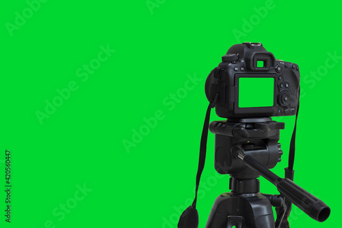 Dslr camera with green screen on the tripod isolated on green background. Green screen camera