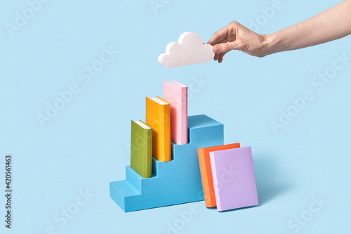 Papercraft cloud in a hand above shelf of books.