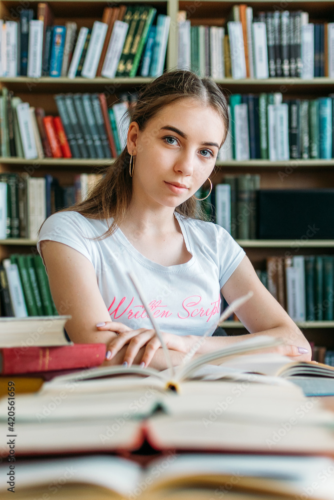 Back to school, reading book, education, library concept. Student girl with book on background of bookshelves in the library. Back to school, reading book, education, library concept. Student girl with book on background of bookshelves in the library.